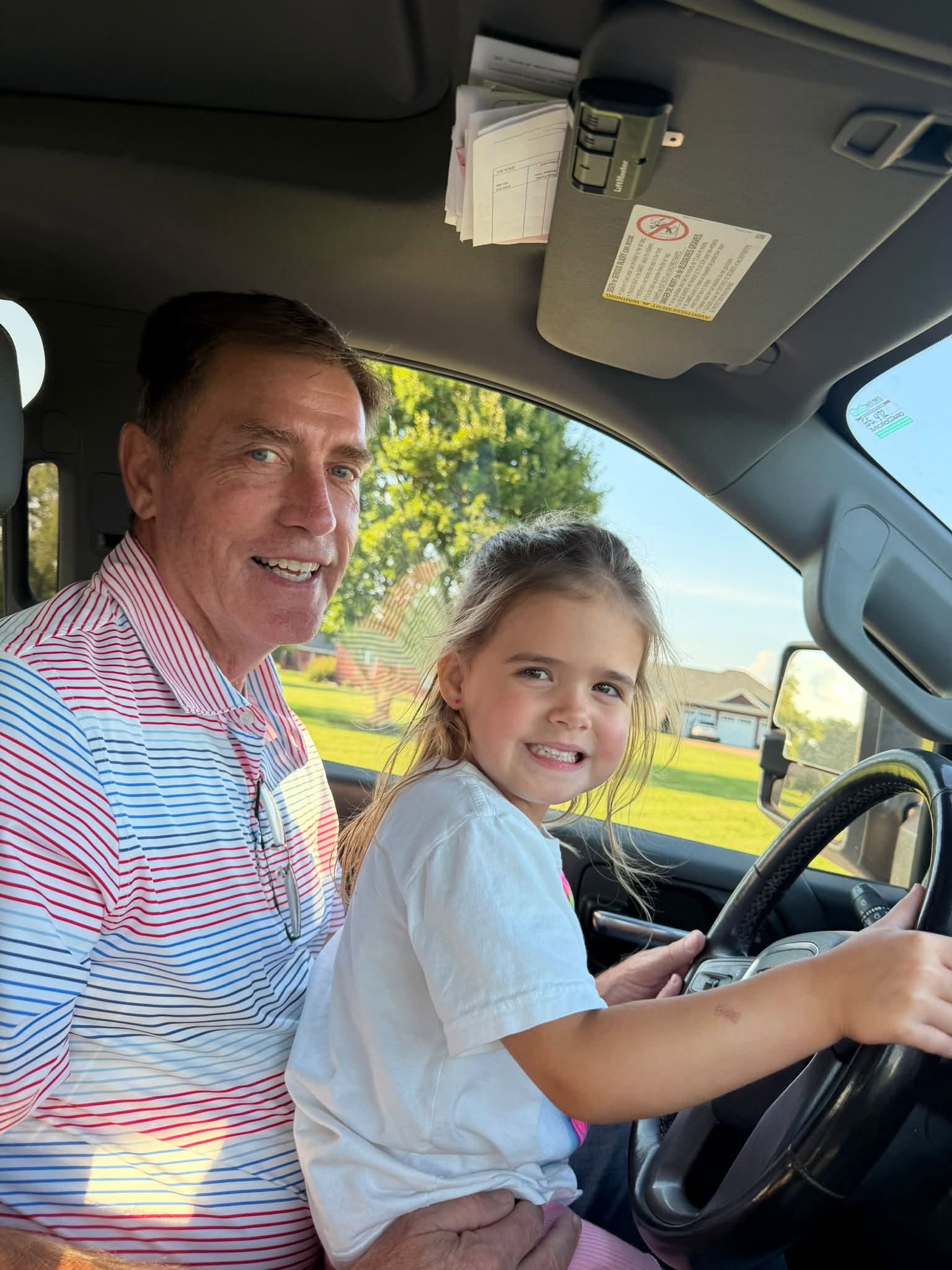 Darryl Watson smiling with a child in the front seat of a truck